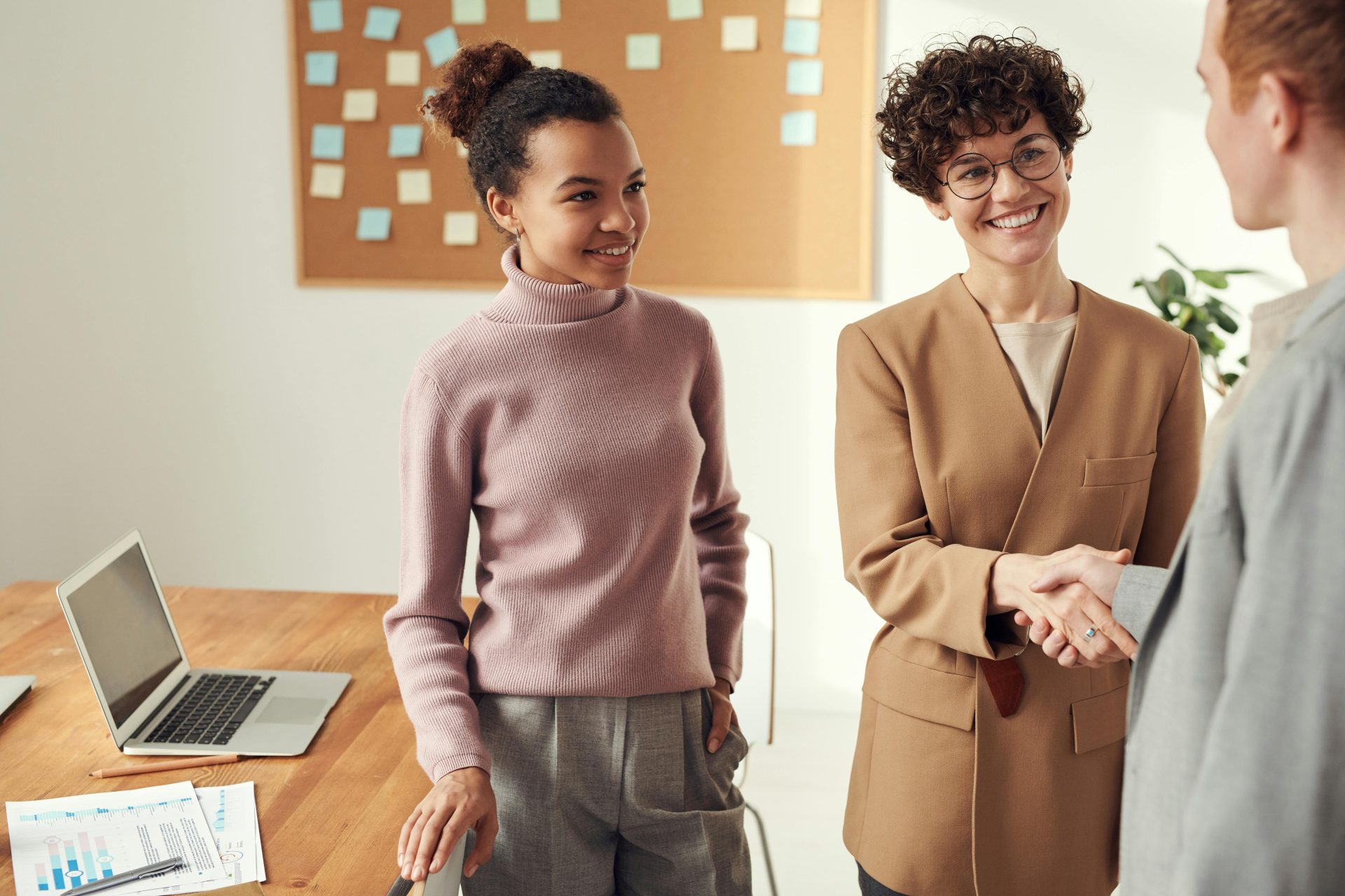 Geschäftspartner im Büro schütteln sich die Hände und lächeln – ein Zeichen für Teamwork und Zusammenarbeit.