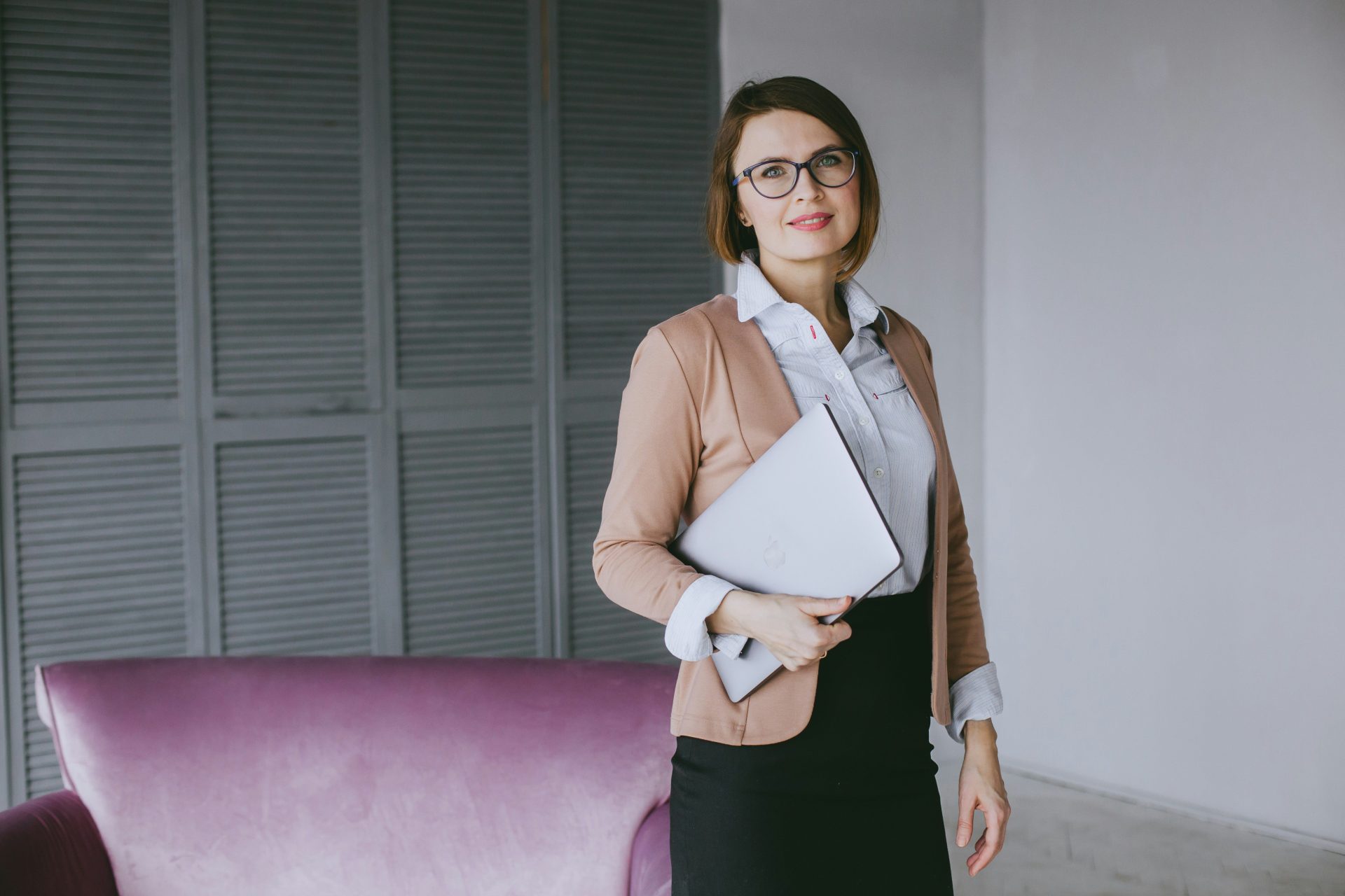 Eine Frau im Business-Anzug, die einen Laptop hält